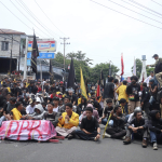 Massa aksi membawa sebuah keranda mini yang di bungkus kain bertuliskan DPR berwarna merah. 