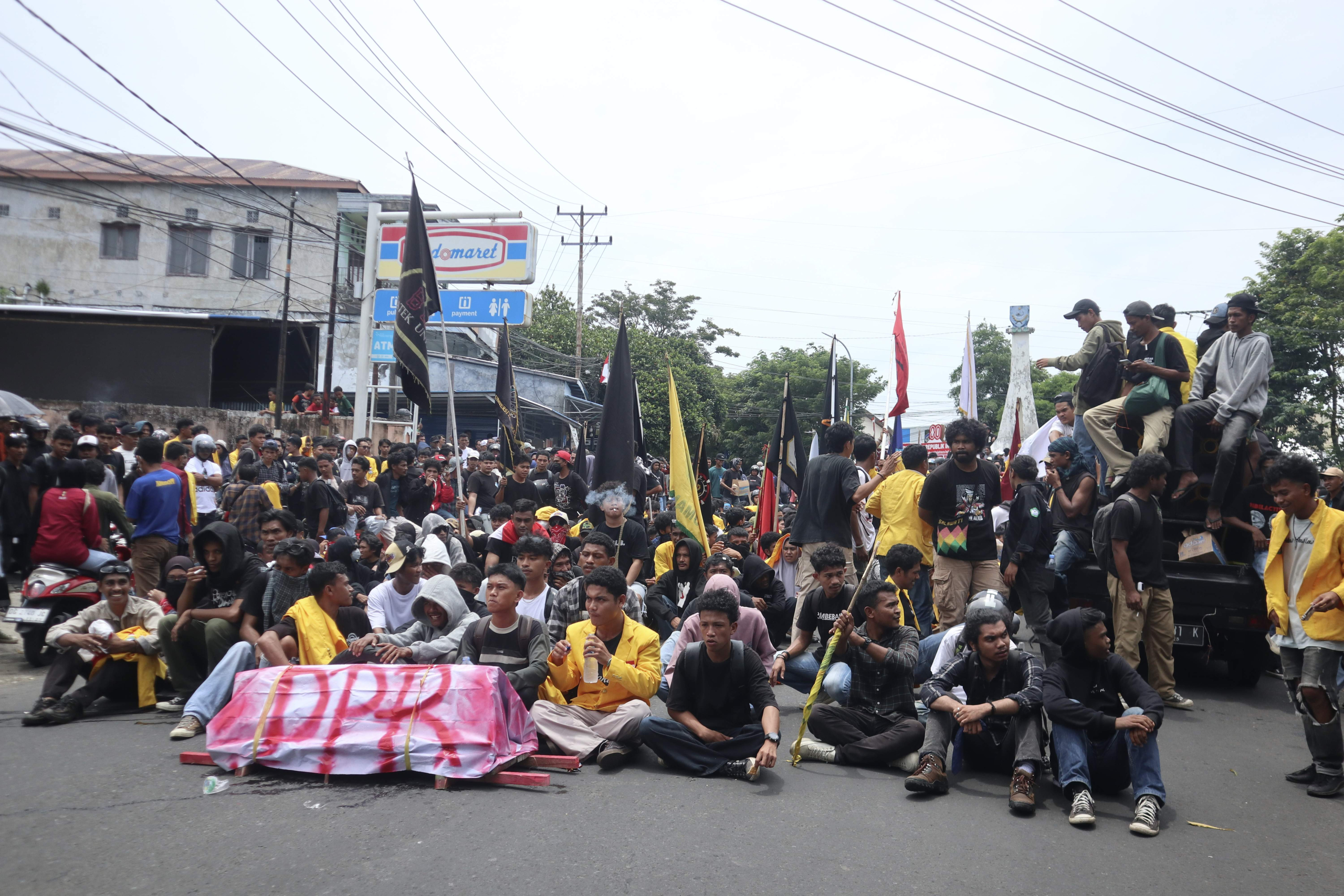 Massa aksi membawa sebuah keranda mini yang di bungkus kain bertuliskan DPR berwarna merah. 